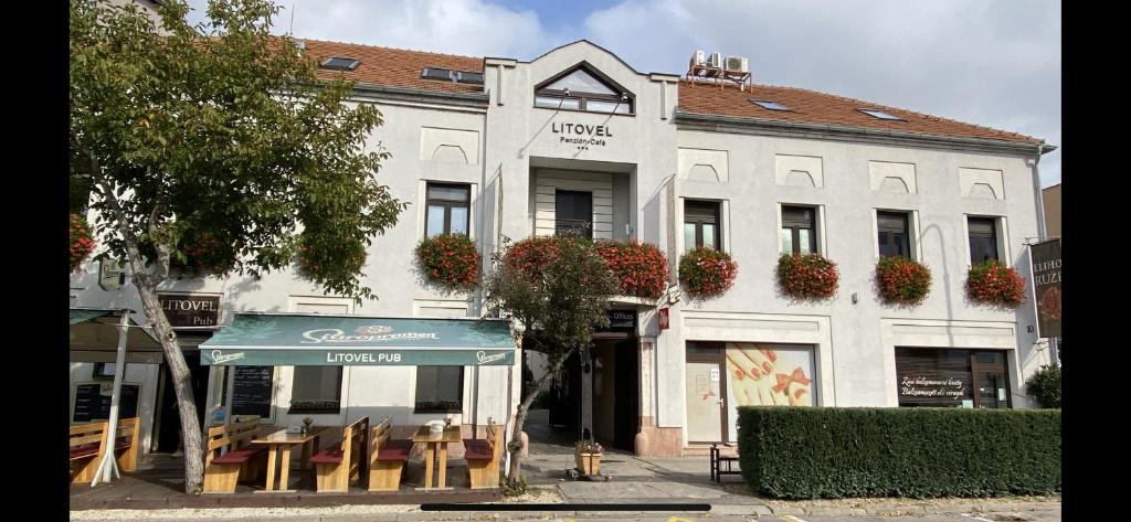 un edificio bianco con una tettoia verde davanti di Hotel Litovel a Komárno