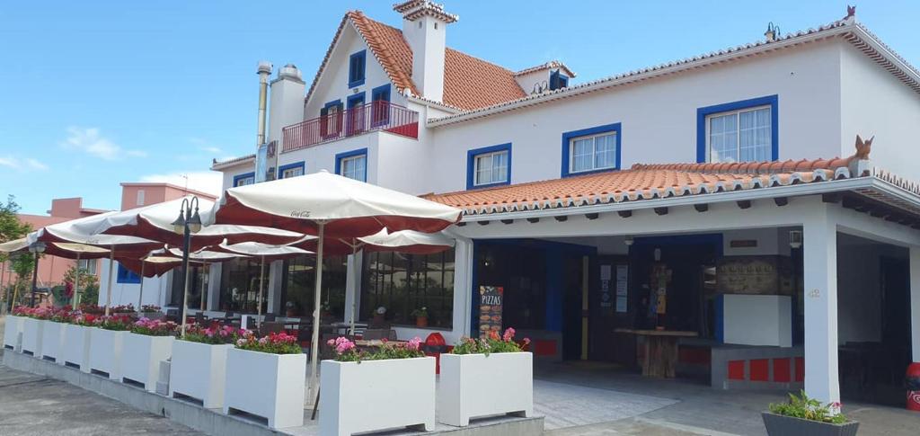 un edificio blanco con sombrillas delante en Hotel O Colmo en Santana