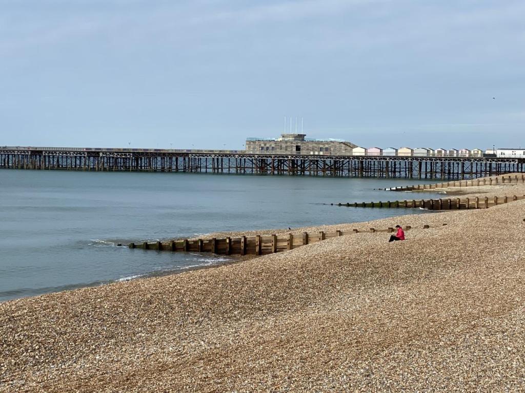 una persona sentada en la playa cerca de un muelle en Astral Lodge en Hastings