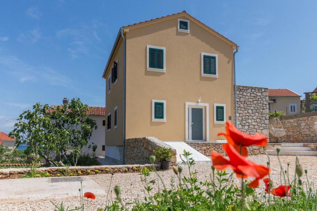 uma casa com uma flor vermelha à frente dela em Villa Lali - New Villa near the sea in Lukoran em Lukoran