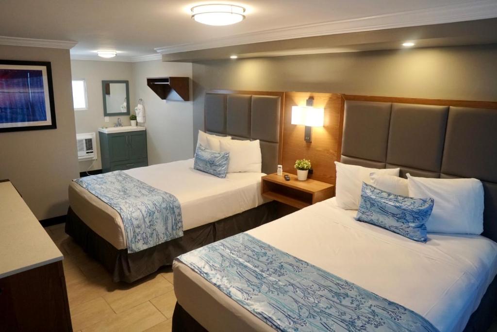 ein Hotelzimmer mit 2 Betten und einem Bad in der Unterkunft Coastal Sands Inn in Wildwood