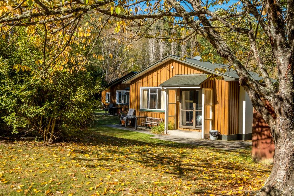 una cabaña en el bosque con un árbol en Alpine Adventure Holiday Park en Hanmer Springs