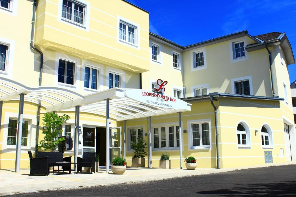 un bâtiment jaune et blanc avec un panneau sur lequel figure un panneau dans l'établissement Hotel Leobersdorfer Hof, à Leobersdorf