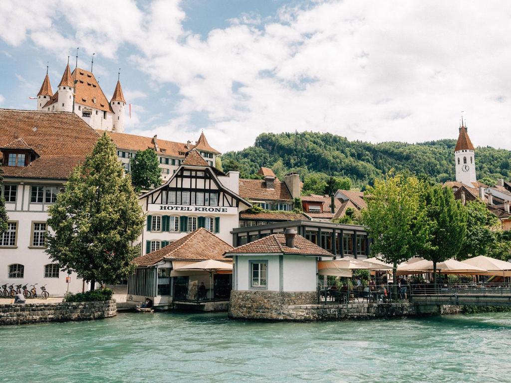 een groep gebouwen aan de rivier in een stad bij Hotel Krone Thun in Thun