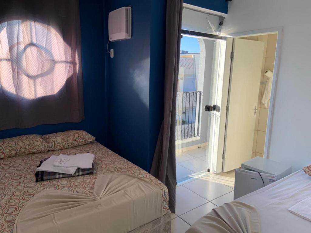 een slaapkamer met een bed en een deur naar een balkon bij Hotel Mão de Fatima in Aparecida