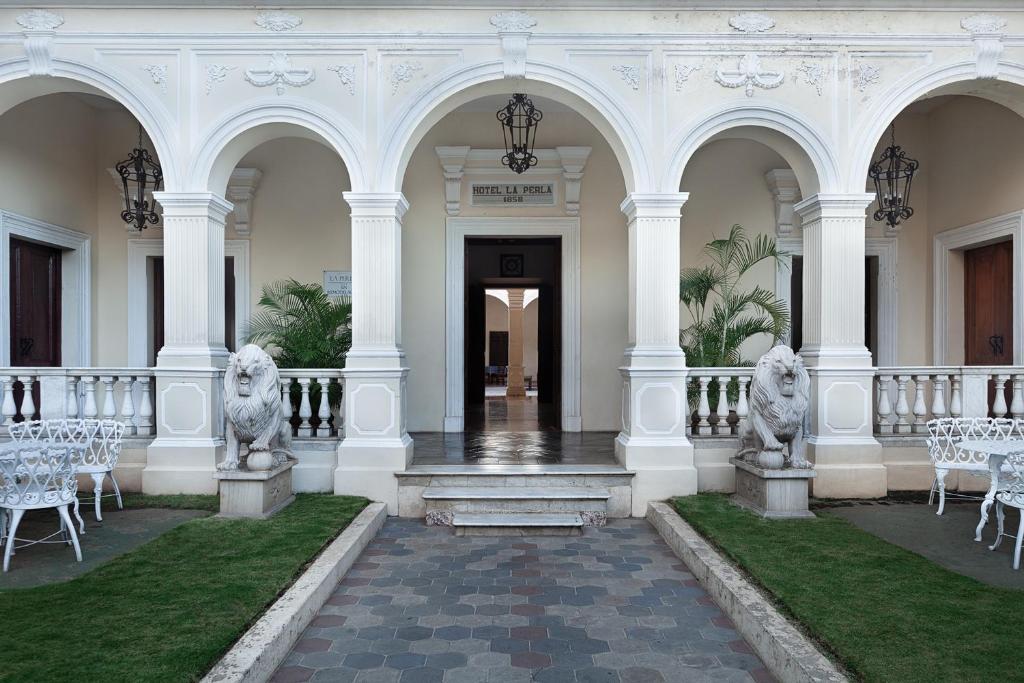 - un bâtiment blanc avec des tables et des chaises blanches dans l'établissement Hotel la Perla Leon, à León