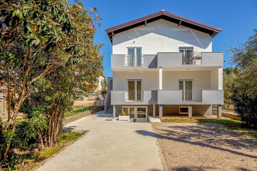 Casa blanca con balcón y árboles en Apartment Lea en Sveti Filip i Jakov