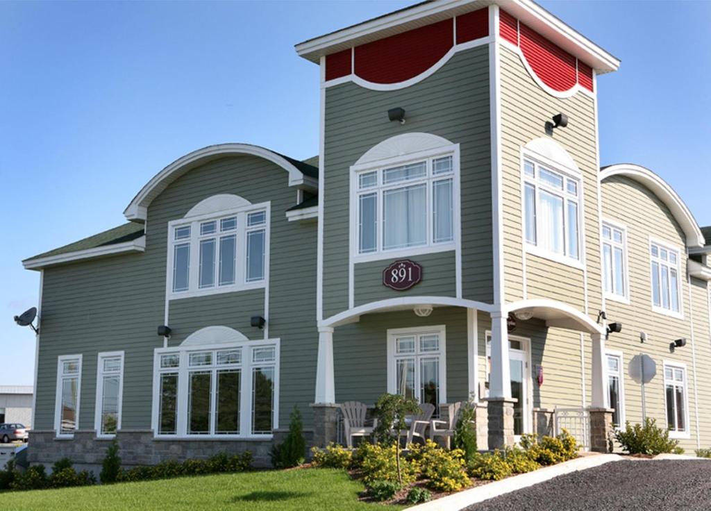 une grande maison avec des finitions rouges et blanches dans l'établissement Hotel La Porte de la Matawinie -Hôtel Matha, à Saint-Jean-de-Matha