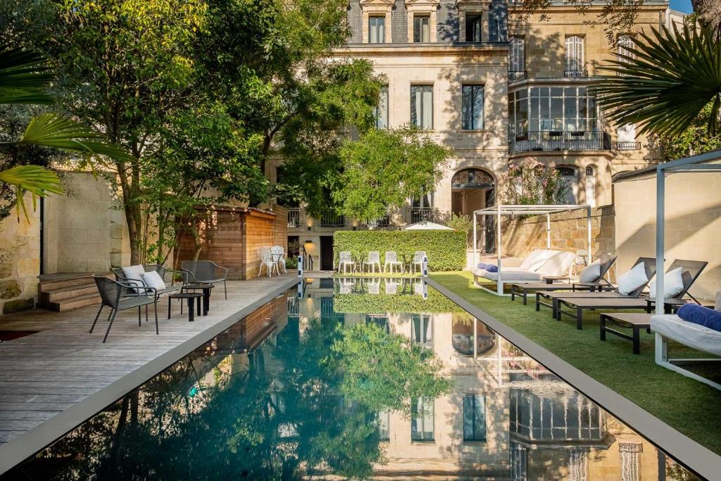 un patio con piscina frente a un edificio en Le Palais Gallien Hôtel & Spa en Burdeos