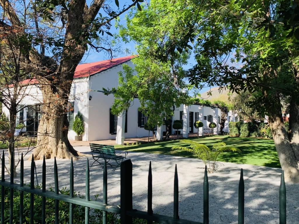 een hek voor een wit gebouw bij de Wingerd B & B in Graaff-Reinet