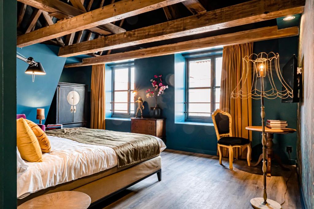 um quarto com paredes azuis, uma cama e uma mesa em MAF Haarlem Boutique Hotel em Haarlem