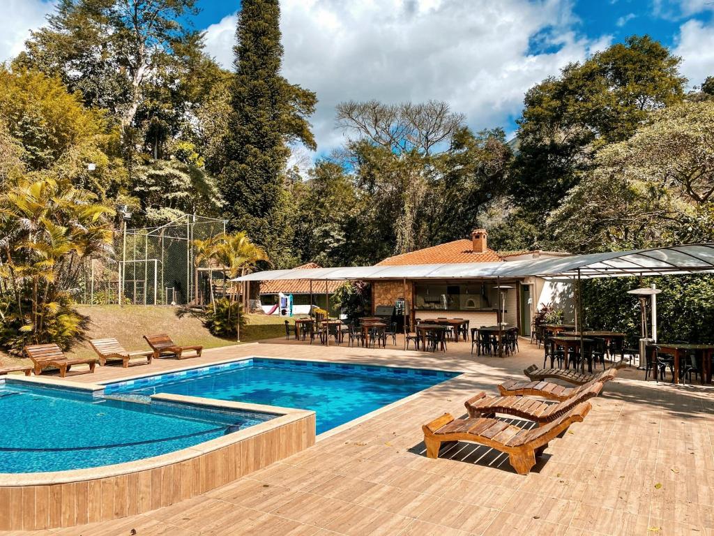 een zwembad met stoelen en tafels en een huis bij Hotel Vila Bavária Petrópolis in Petrópolis