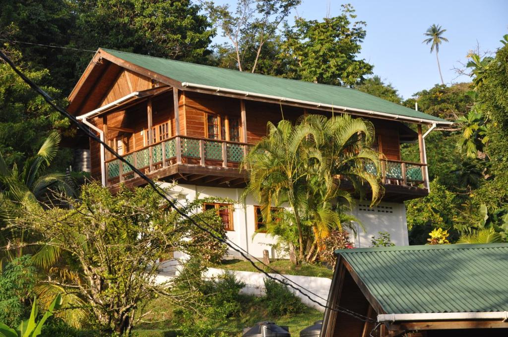 uma casa de madeira com um telhado verde em Castara Villas em Castara