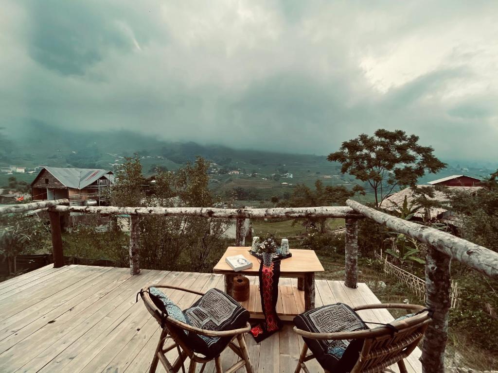 um deque de madeira com uma mesa e 2 cadeiras em H’nee House Ta Van em Sapa