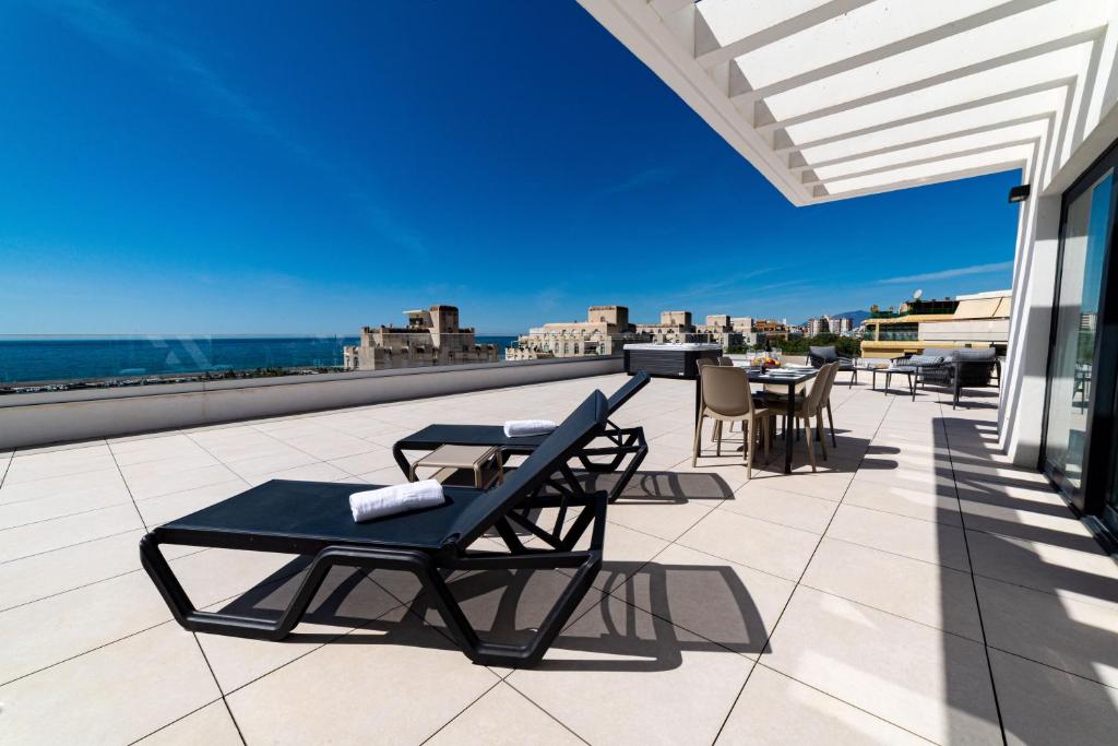 un patio con sillas y mesas en la azotea en Aqua Apartments Bellamar, Marbella en Marbella