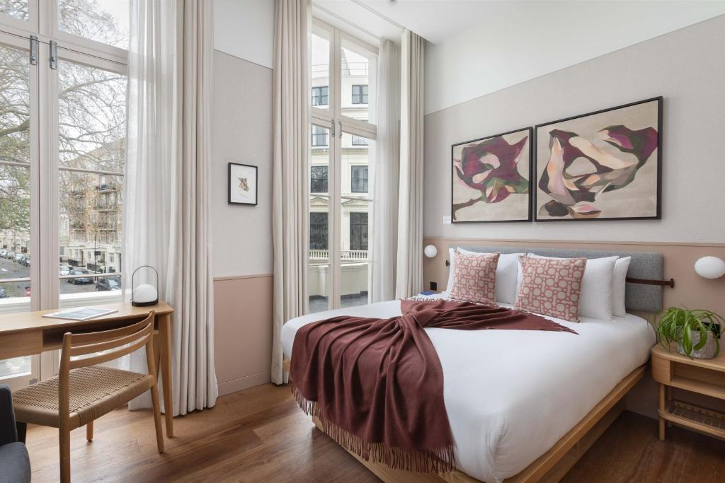 1 dormitorio con 1 cama, escritorio y ventanas en Inhabit Queen's Gardens, a Member of Design Hotels en Londres