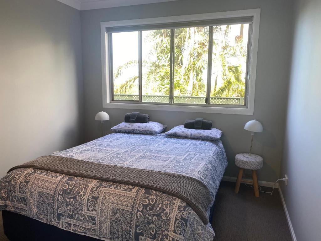 Schlafzimmer mit einem Bett und einem großen Fenster in der Unterkunft Central Oasis in Coffs Harbour