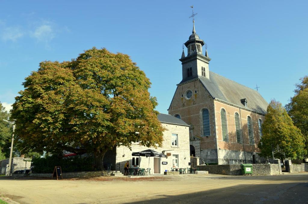 une église avec une tour et un arbre devant elle dans l'établissement B&B Le Vieux Marronnier, à Foy-Notre-Dame