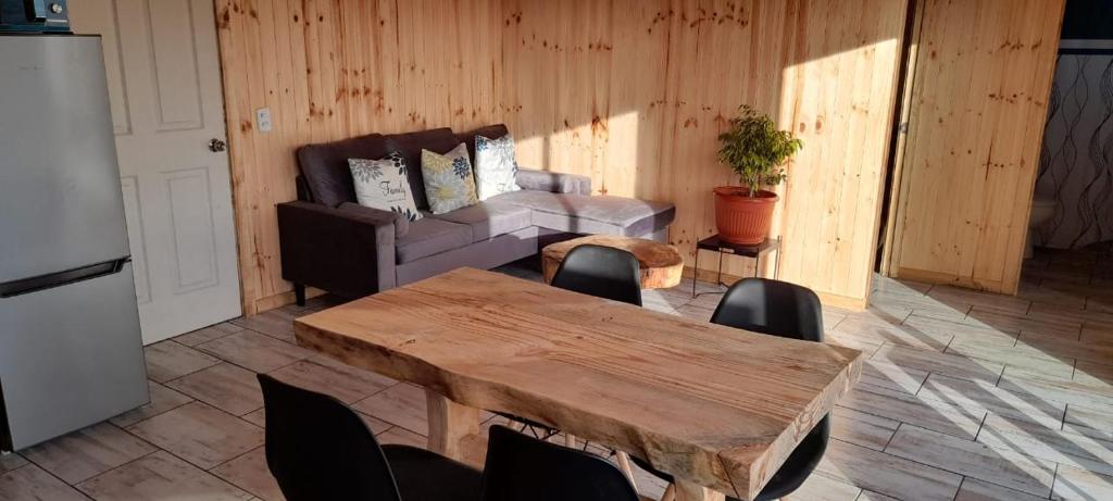 uma sala de estar com uma mesa de madeira e um sofá em Cabaña La Puntilla em Vichuquén