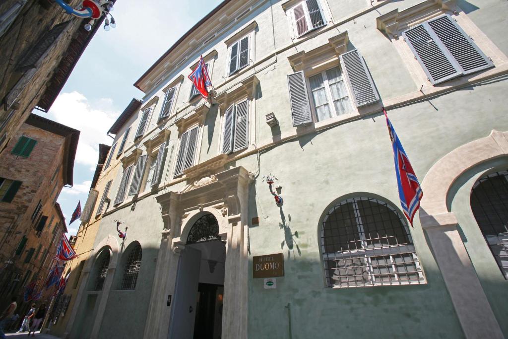 a building with two flags on the side of it at Hotel Duomo in Siena