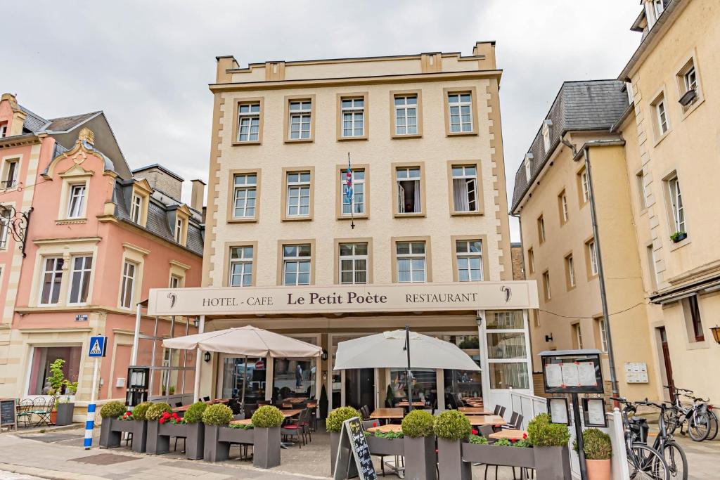 Hôtel Le Petit Poète في اتشتيرناتش: مبنى امامه طاولات ومظلات