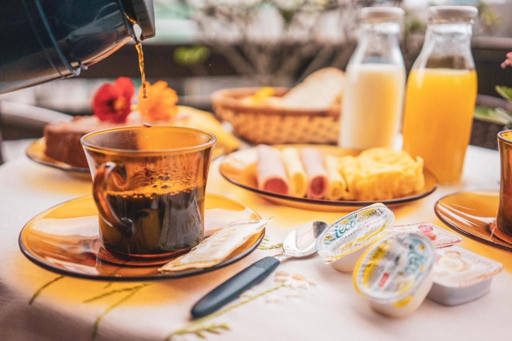 Eine Person schüttet Kaffee in eine Tasse auf einen Tisch. in der Unterkunft Água Marinha de Bombas - Bombinhas in Bombinhas