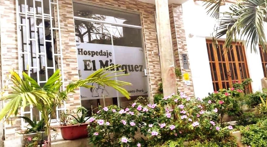 una señal en el lado de un edificio con plantas en Hospedaje EL MARQUEZ Expat en Máncora