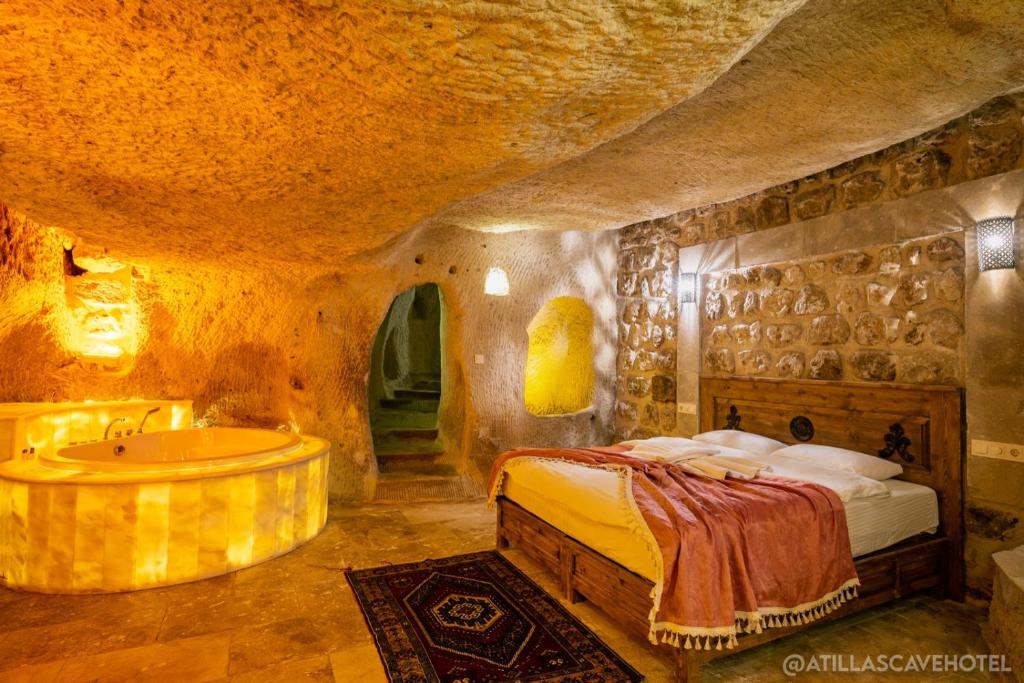 1 dormitorio con cama y bañera en una cueva en Atilla's Cave Hotel en Nevşehir