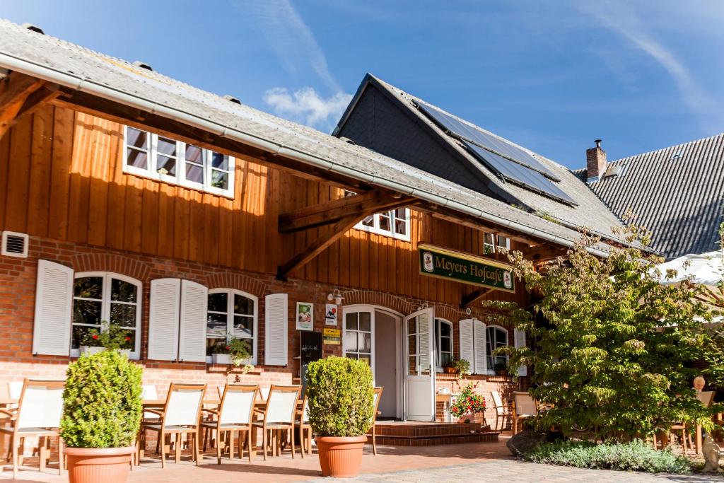 a wooden building with chairs in front of it at Meyers Hofcafe in Isenbüttel