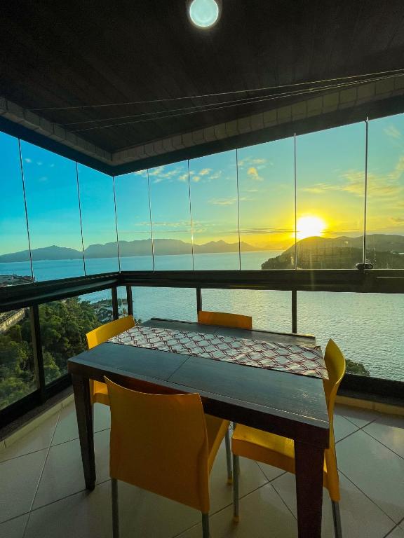 un tavolo con sedie in una camera con vista sull'oceano di Apartamento em frente ao clube do Porto Real Resort ad Angra dos Reis