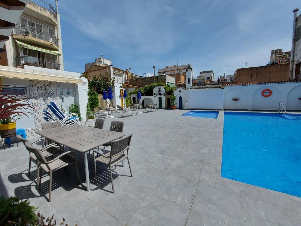 um pátio com uma mesa e cadeiras ao lado de uma piscina em Hotel Mediterrani Express em Calella