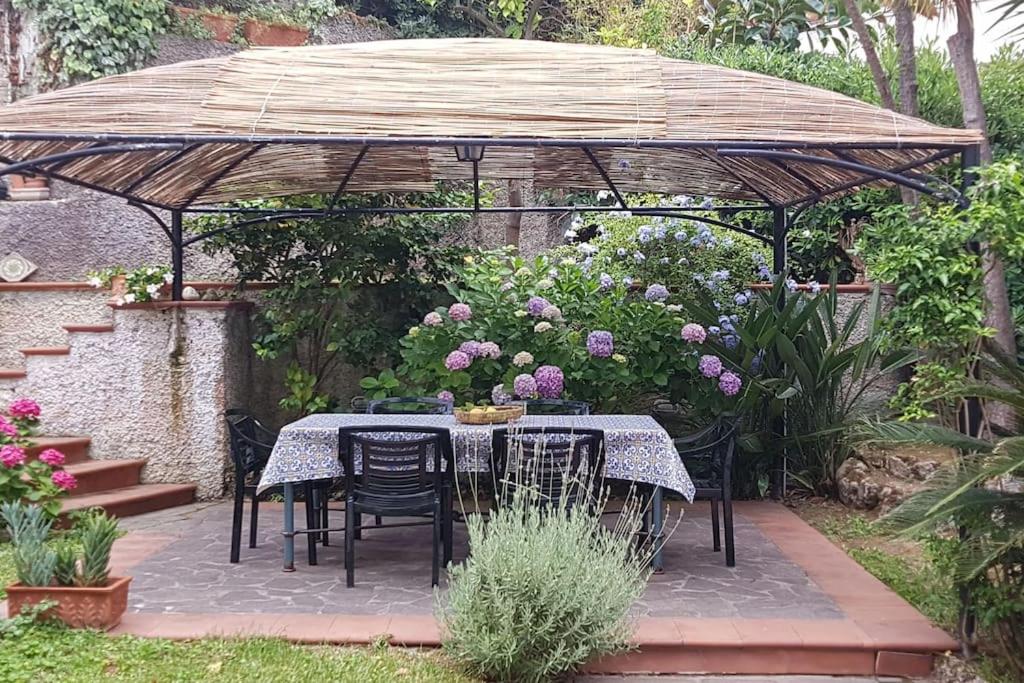 una mesa y sillas bajo una sombrilla en un jardín en Giardino Mediterraneo en Ischia