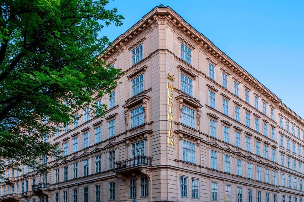 un gran edificio de ladrillo con ventanas y un árbol en Le Méridien Vienna, en Viena