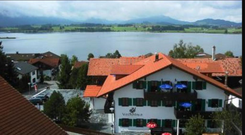 um edifício com um telhado laranja ao lado de um lago em Ferienhaus Vitushöhle em Füssen