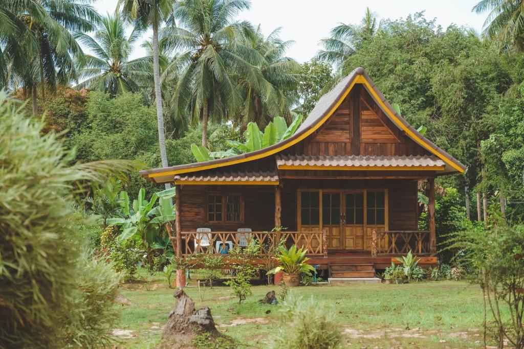 uma pequena casa de madeira num campo com palmeiras em Kohjum Freedom Resort em Ko Jum