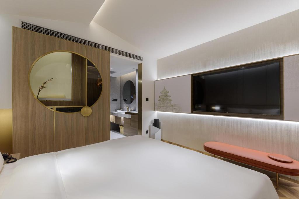 una camera da letto con un grande letto bianco e una televisione di Atour S Hotel Beijing Zhongguancun Beiwai a Pechino