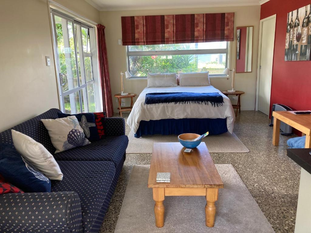 a living room with a bed and a table at The Back Garden in Waihi Beach