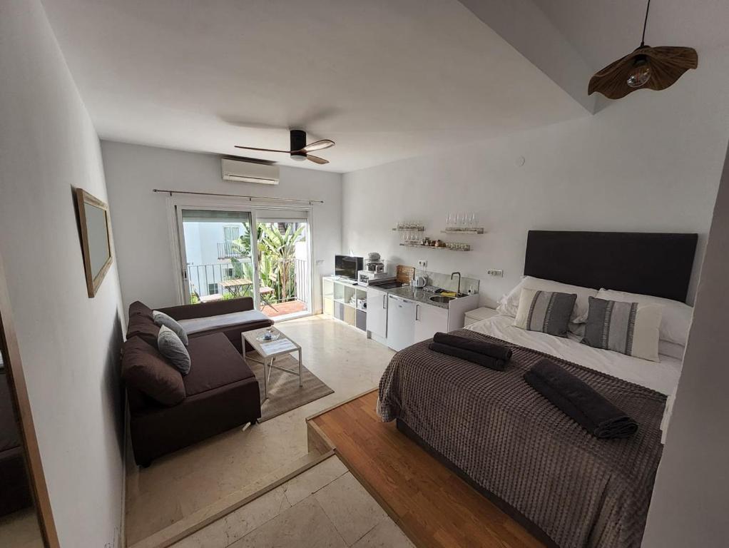 een slaapkamer met een bed en een bank en een keuken bij Tranquility studio apartment in Málaga