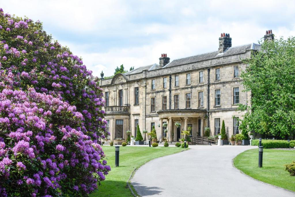 une vieille maison avec des fleurs violettes devant elle dans l'établissement Beamish Hall Country House Hotel, BW Premier Collection, à Stanley