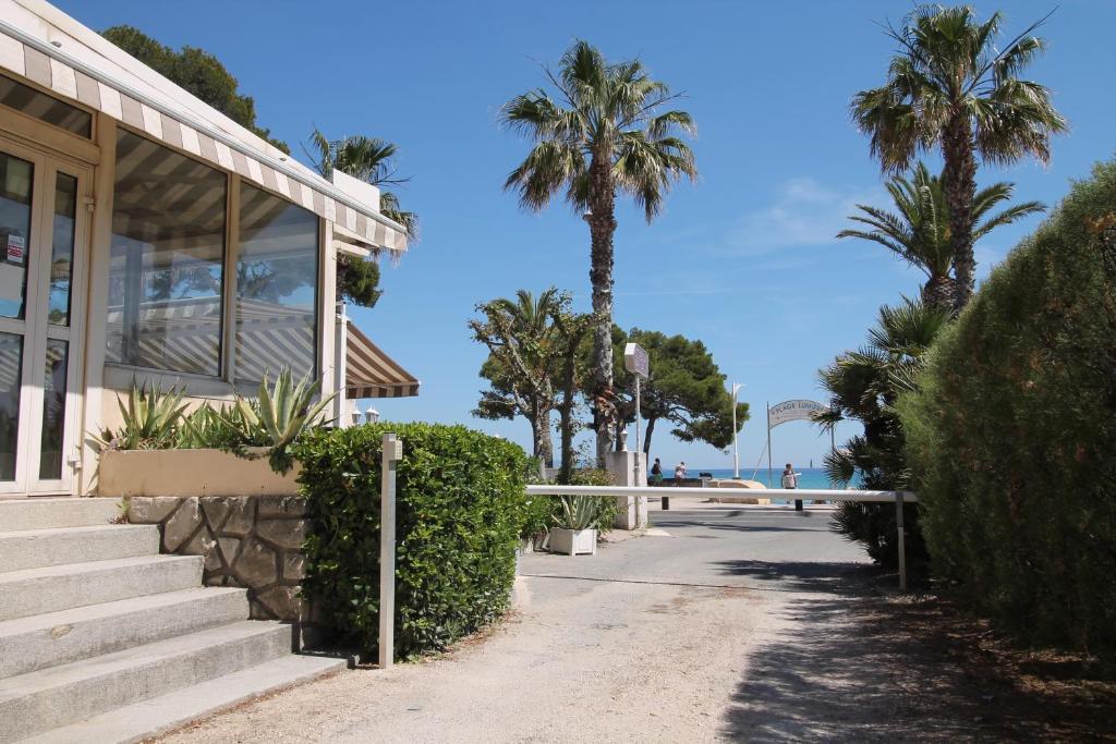 un edificio con escaleras y palmeras en la playa en Hotel Restaurant Miramar L'orchidée en La Ciotat