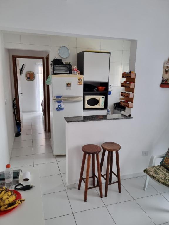 cocina con 2 taburetes y encimera en Flat boqueirão en Praia Grande