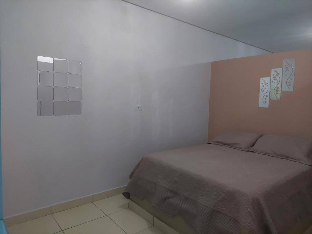 een slaapkamer met een bed en een witte muur bij Kitnet Vila Marcela in Petrolina