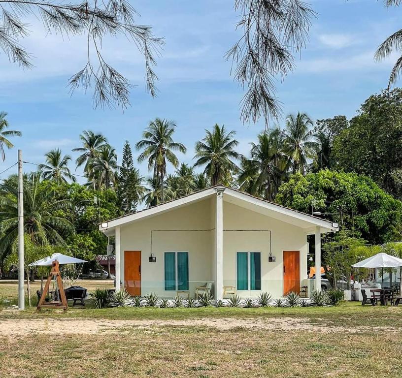 una pequeña casa blanca con palmeras en el fondo en DamaiiKu en Cherating