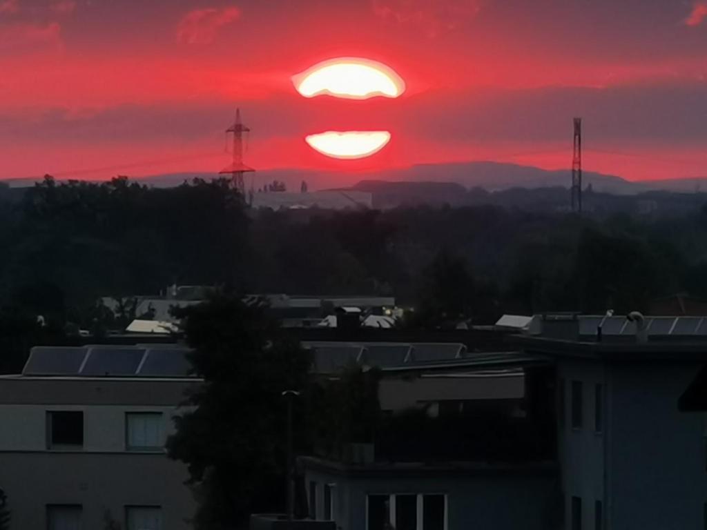 um pôr-do-sol sobre uma cidade com um céu vermelho em Skyline klimatisierte Dachgeschoss-Wohnung in Dornbirn mit Blick ins Rheintal em Dornbirn