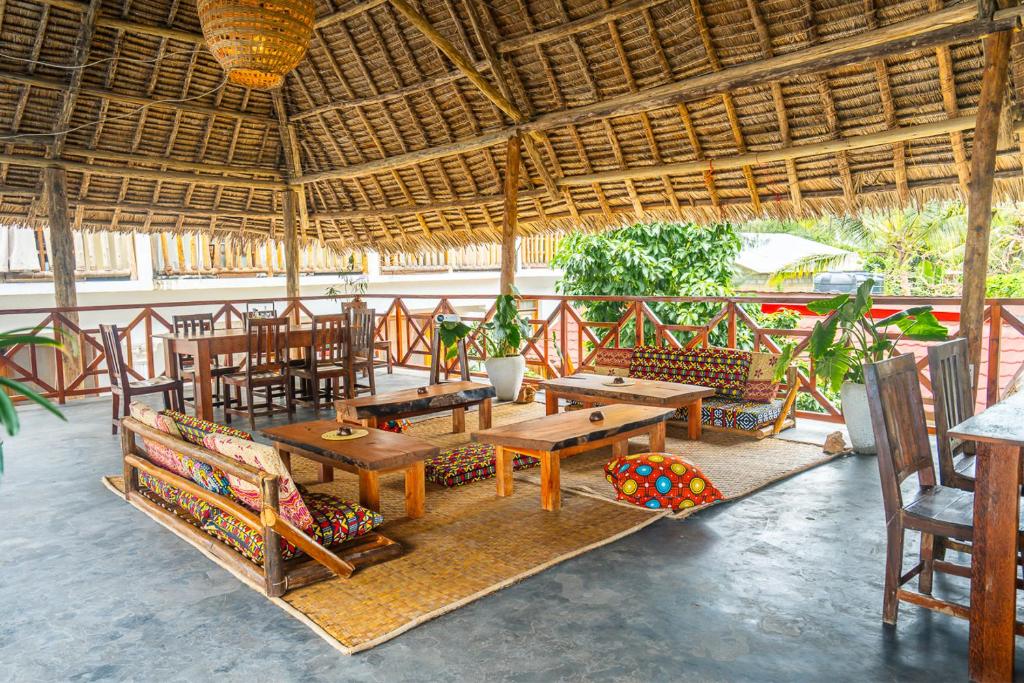 un restaurante con mesas y sillas de madera y techo de paja en La Fontana Restaurant & Bungalows, en Kendwa