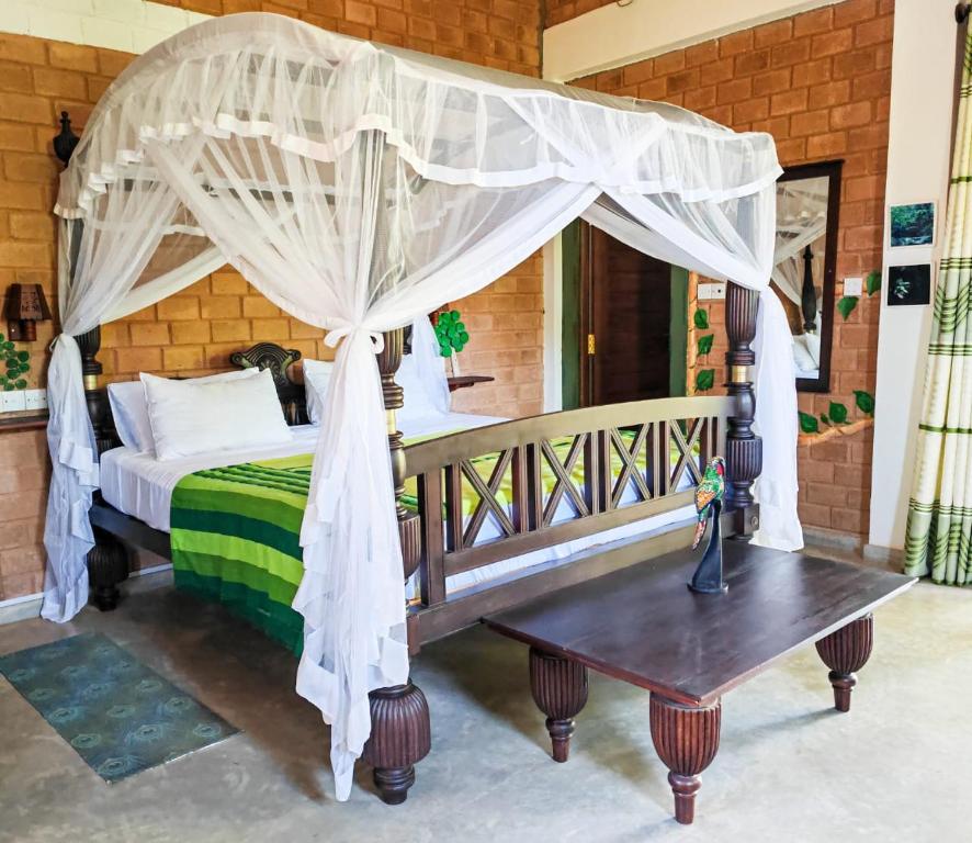 um quarto com uma cama de dossel e uma mesa de madeira em Villa Lyvie ayurvedic hotel em Tangalle