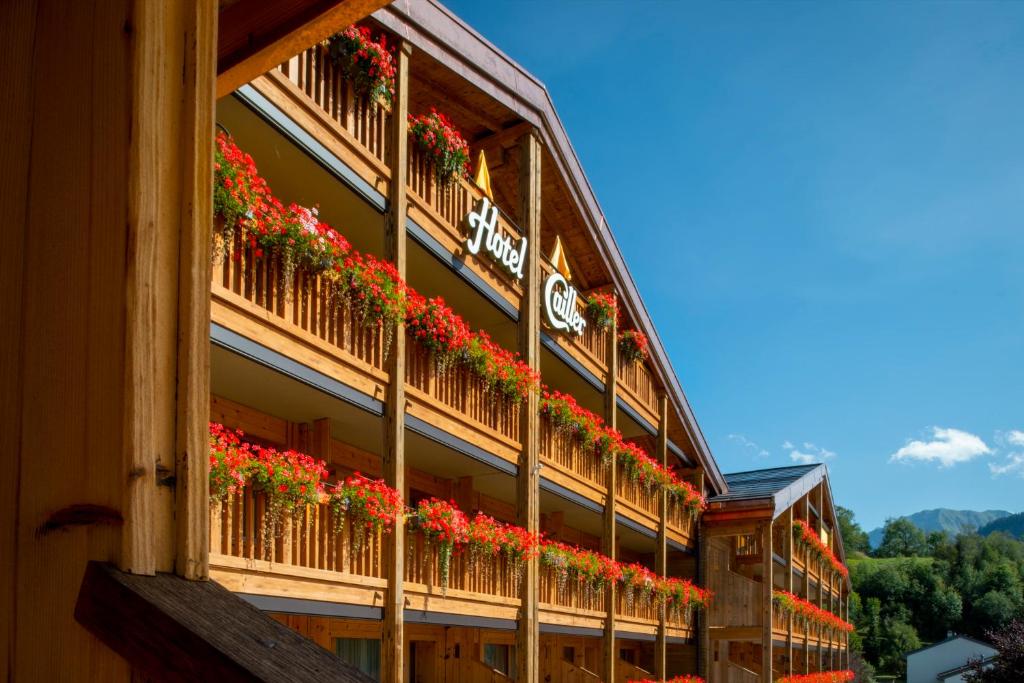 um edifício com flores vermelhas nas varandas em Hôtel Cailler & Bains de la Gruyère em Charmey