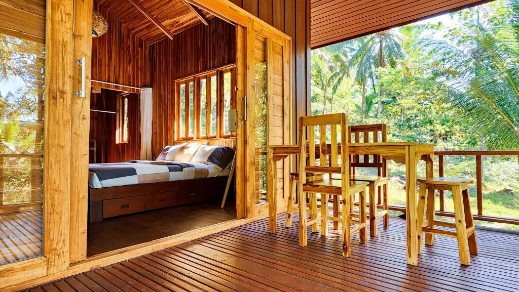 - une chambre avec un lit, une table et des chaises sur une terrasse couverte dans l'établissement Baan Bhuwann Forest Chalet, à Ko Pha Ngan