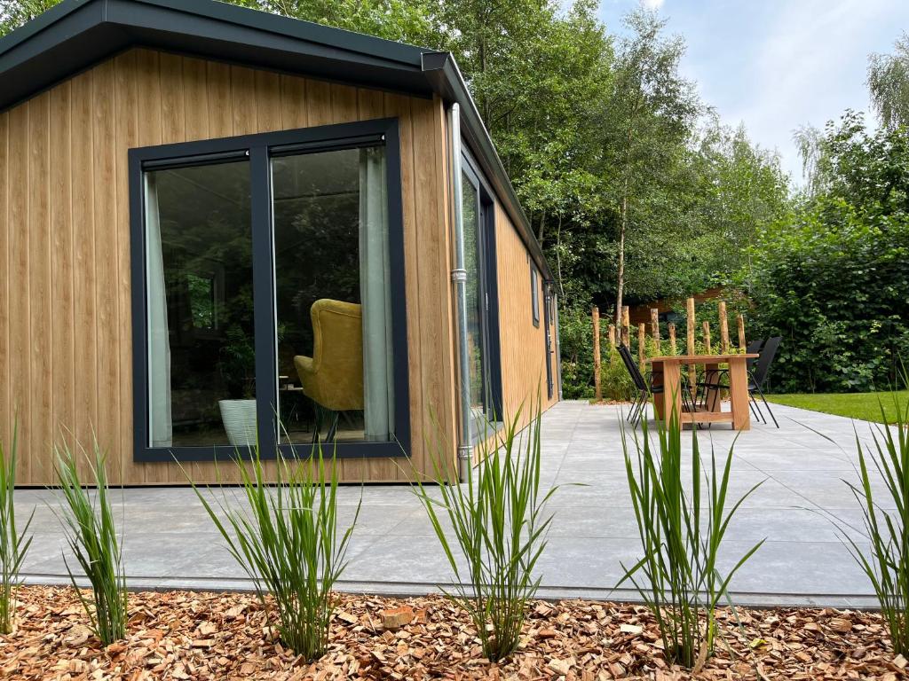 une petite maison avec une grande fenêtre dans un jardin dans l'établissement Landzicht Natuur Rust en Ruimte, à Oosterwolde