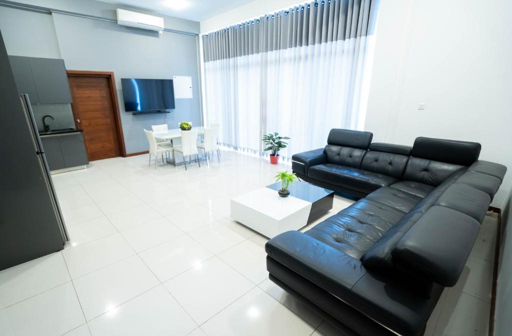 sala de estar con sofá de cuero negro y mesa en Quest Colombo Residencies, en Talawatugoda